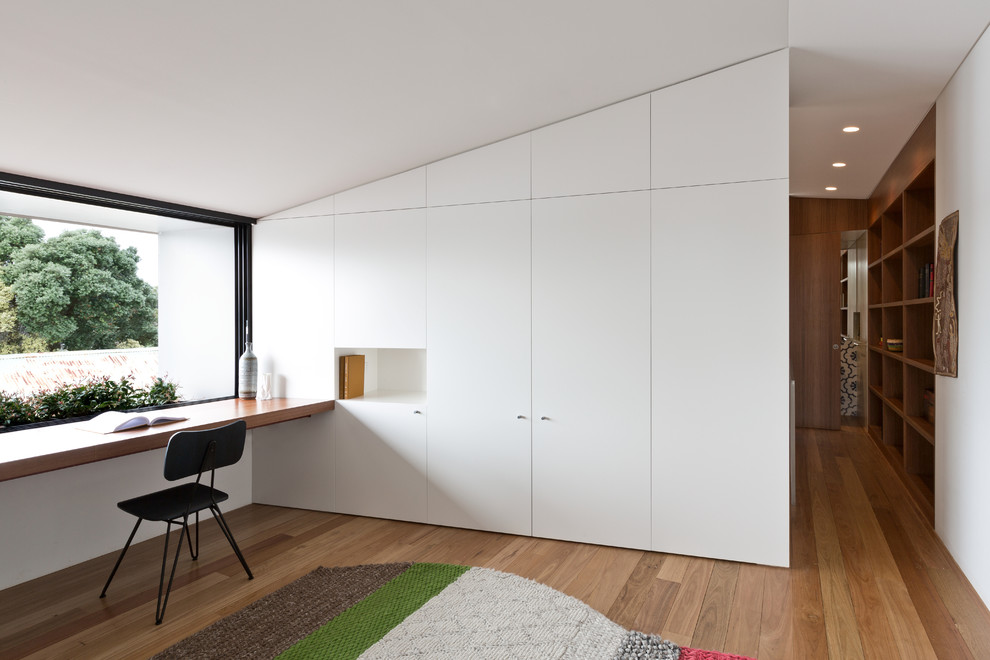 Esempio di uno studio contemporaneo con pareti bianche, pavimento in legno massello medio e scrivania incassata