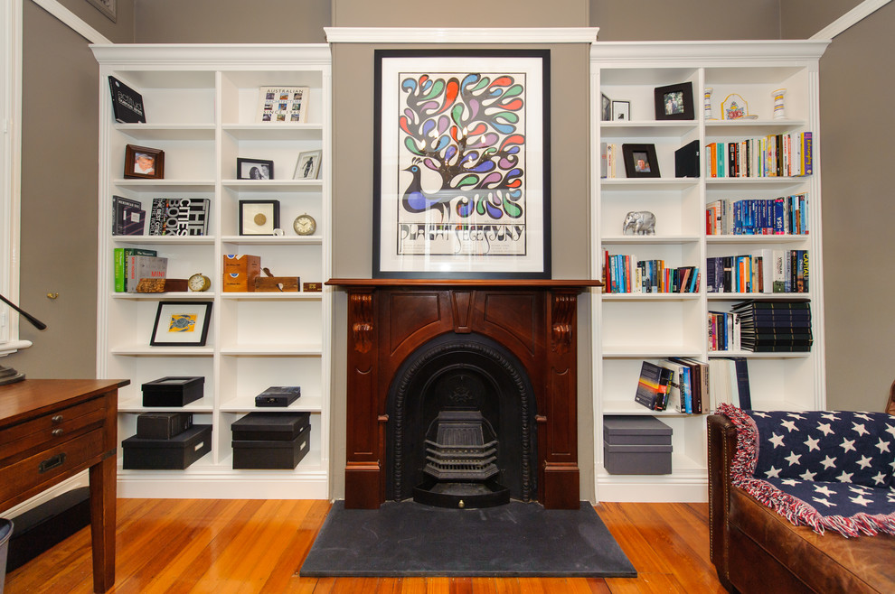 シドニーにある高級な広いヴィクトリアン調のおしゃれな書斎 (グレーの壁、淡色無垢フローリング、標準型暖炉、木材の暖炉まわり、自立型机) の写真