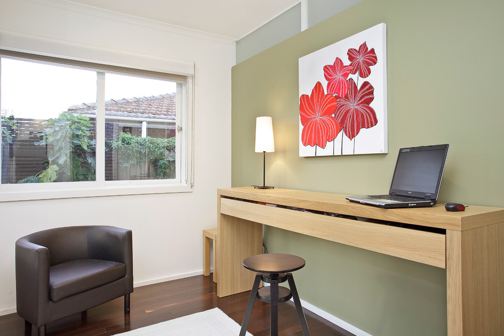 Réalisation d'un bureau design avec un mur vert, parquet foncé et un bureau indépendant.