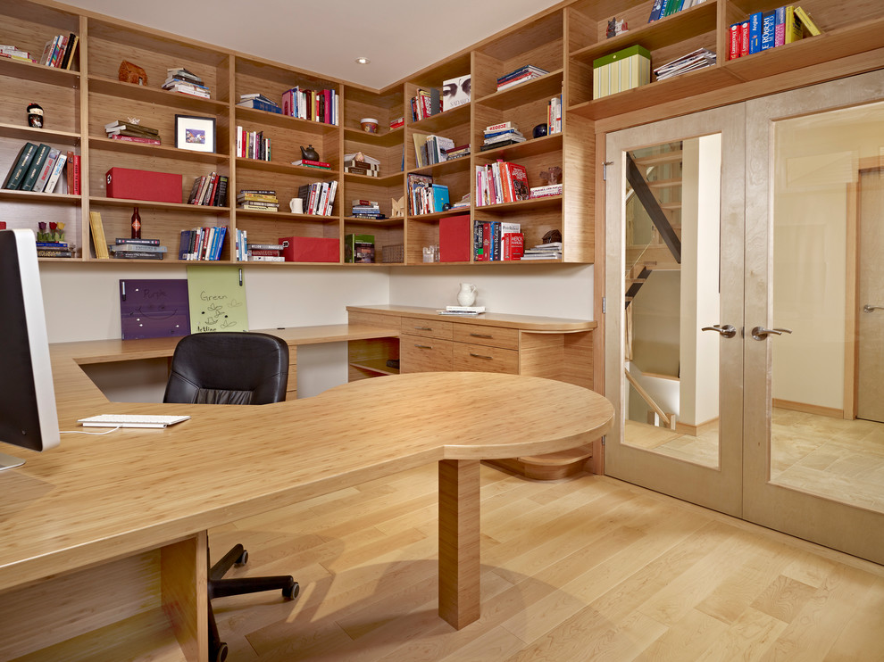 Modern inredning av ett mellanstort hemmabibliotek, med beige väggar, bambugolv och ett inbyggt skrivbord