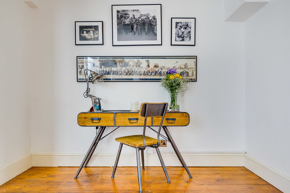Ejemplo de despacho urbano con paredes blancas, suelo de madera en tonos medios, escritorio independiente y suelo marrón