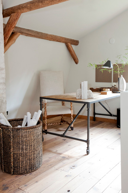 Lantlig inredning av ett stort hobbyrum, med beige väggar, mellanmörkt trägolv och ett fristående skrivbord