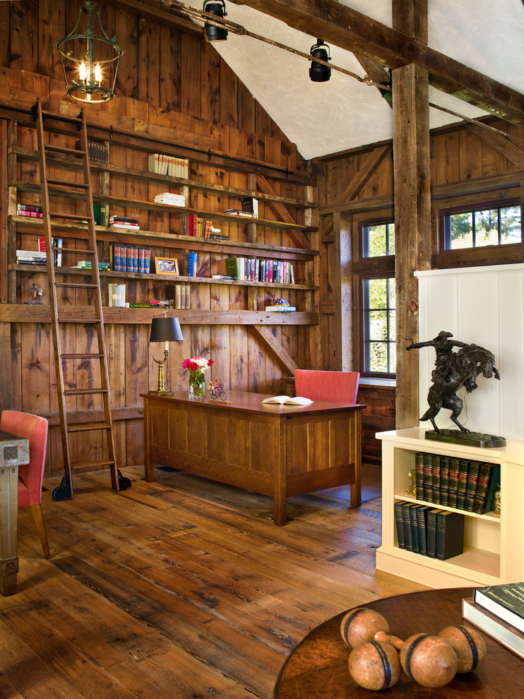 Inspiration för stora klassiska hemmabibliotek, med ett fristående skrivbord, beige väggar och ljust trägolv