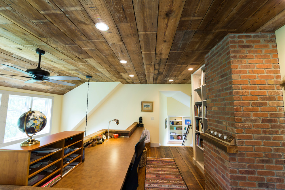 Imagen de despacho rural con suelo de madera oscura, marco de chimenea de ladrillo, escritorio empotrado y paredes blancas