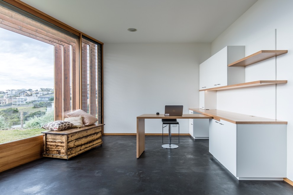 На фото: рабочее место среднего размера в современном стиле с встроенным рабочим столом, белыми стенами и бетонным полом без камина с