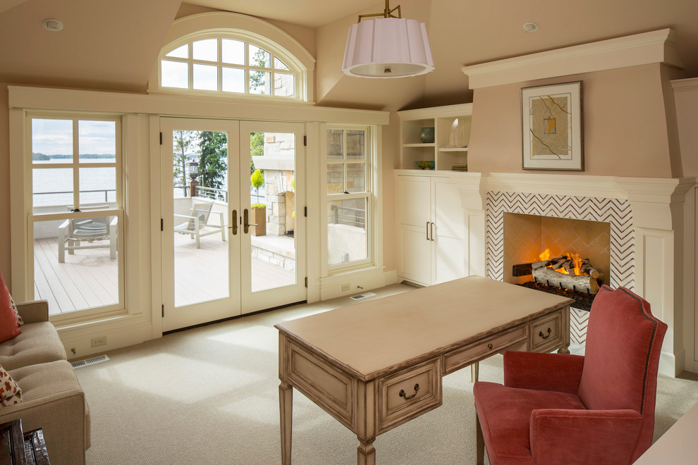 Photo of a coastal study in Minneapolis with beige walls, carpet, a standard fireplace, a tiled fireplace surround, a freestanding desk, beige floors and a chimney breast.