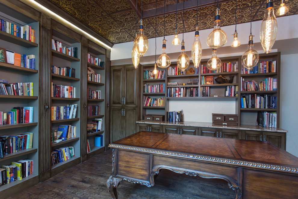 Mediterranes Lesezimmer mit weißer Wandfarbe, dunklem Holzboden, freistehendem Schreibtisch und braunem Boden in Austin