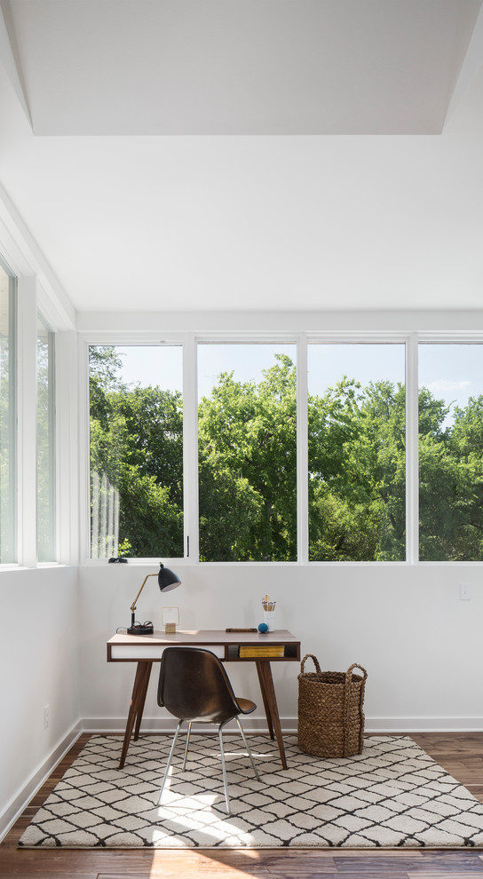 Immagine di uno studio minimalista con pareti bianche, parquet scuro, scrivania autoportante e pavimento marrone