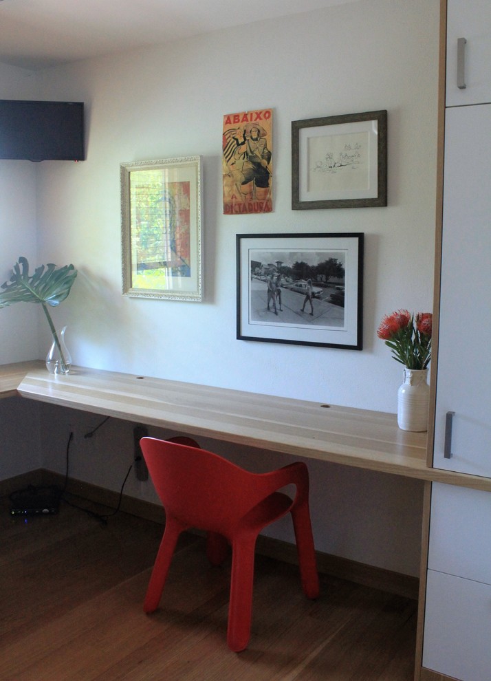 Mittelgroßes Skandinavisches Arbeitszimmer ohne Kamin mit Arbeitsplatz, weißer Wandfarbe, hellem Holzboden und Einbau-Schreibtisch in Austin