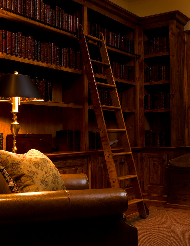 Immagine di uno studio american style di medie dimensioni con libreria, pareti beige e pavimento in legno massello medio