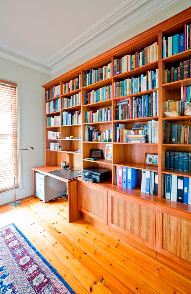 Idéer för att renovera ett stort vintage hemmabibliotek, med vita väggar, mellanmörkt trägolv och ett inbyggt skrivbord