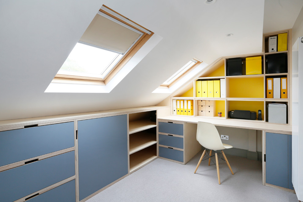 Inredning av ett modernt arbetsrum, med gula väggar, ett inbyggt skrivbord och grått golv