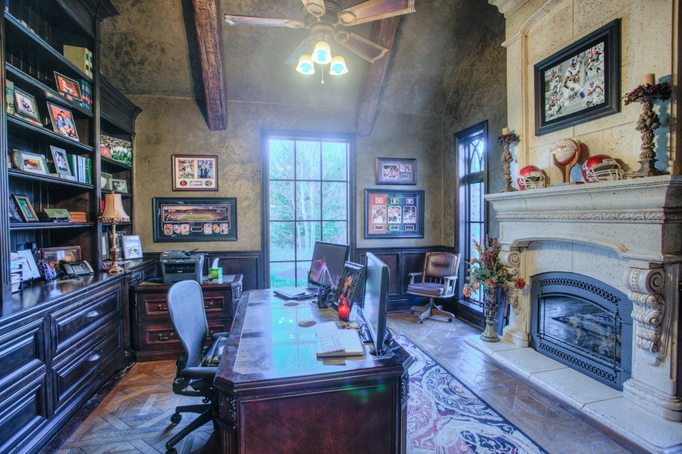 Cette image montre un grand bureau chalet avec un mur gris, un sol en bois brun, une cheminée standard, un manteau de cheminée en béton, un bureau indépendant et un sol marron.