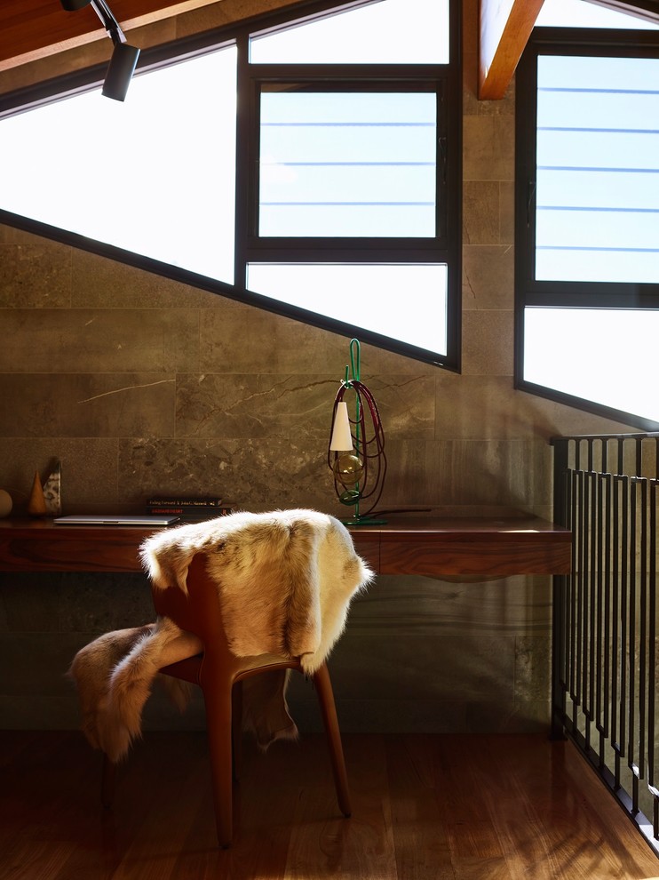 Modernes Arbeitszimmer mit grauer Wandfarbe, braunem Holzboden, Einbau-Schreibtisch und braunem Boden in Brisbane