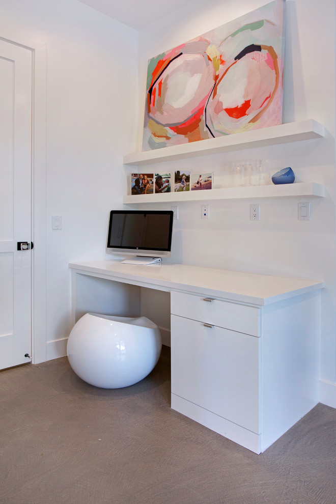 Idee per un ufficio design con pareti bianche, pavimento in cemento e scrivania incassata
