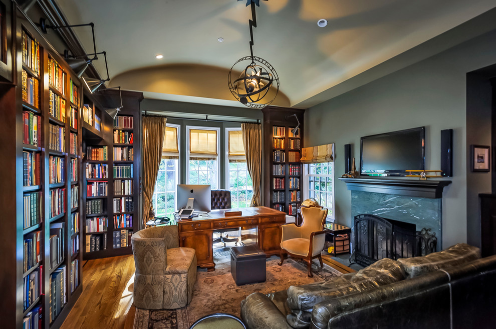 Example of a huge classic freestanding desk medium tone wood floor study room design in San Francisco with a standard fireplace and gray walls