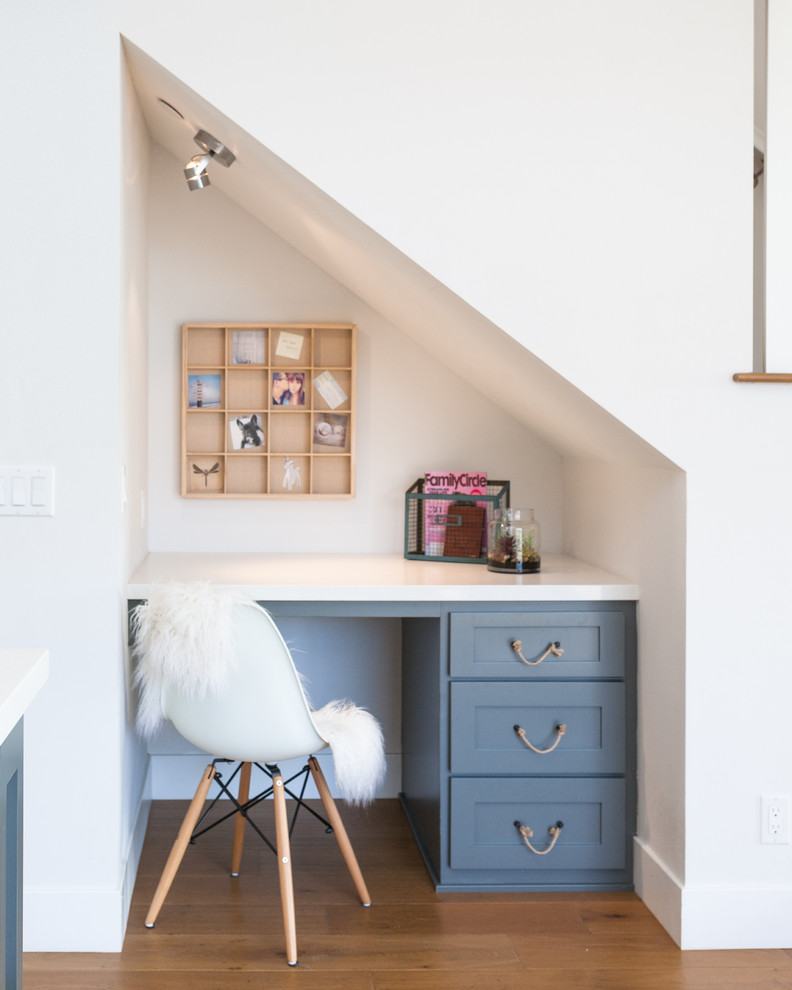 Home office - coastal built-in desk dark wood floor home office idea in Orange County with white walls