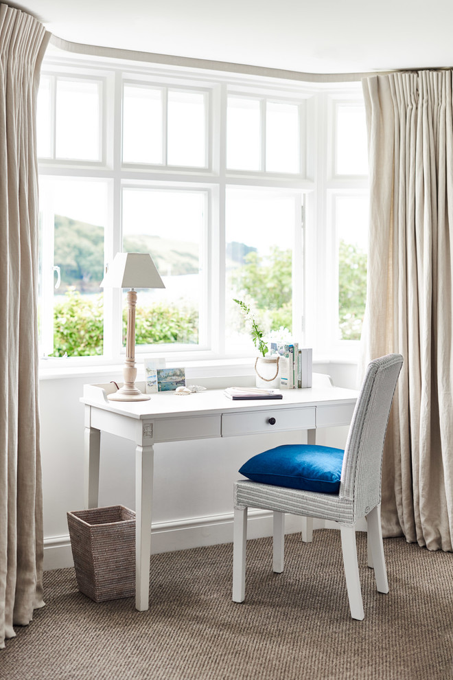 This is an example of a coastal study in Wiltshire with white walls, carpet, a freestanding desk and beige floors.