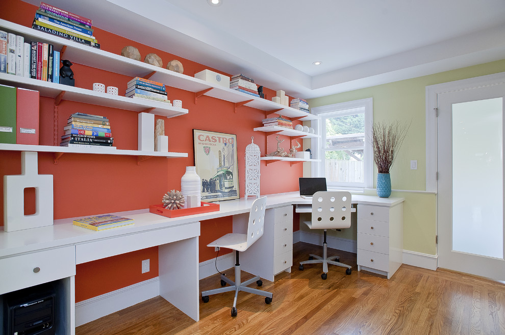 Home office - coastal built-in desk medium tone wood floor home office idea in San Francisco with orange walls