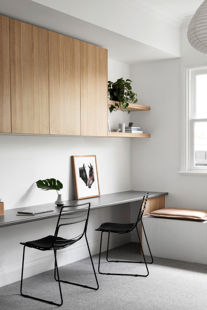 Ejemplo de despacho costero de tamaño medio con paredes blancas, moqueta, suelo gris y escritorio empotrado