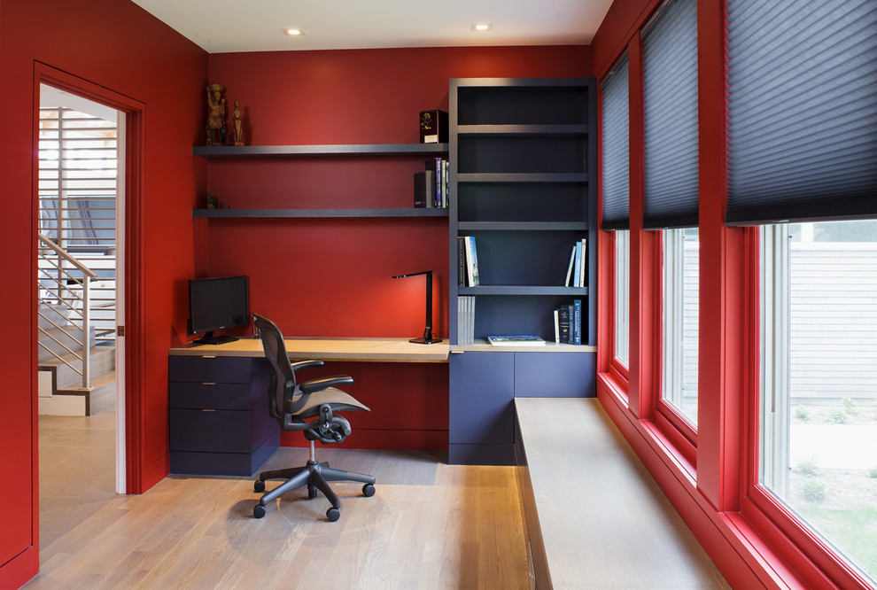Cette image montre un bureau marin avec un mur rouge, parquet clair, aucune cheminée, un bureau intégré et un sol beige.