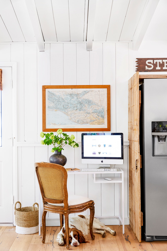 Kleines Maritimes Arbeitszimmer mit weißer Wandfarbe, hellem Holzboden, freistehendem Schreibtisch und Arbeitsplatz in Los Angeles