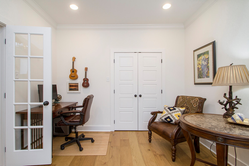 Immagine di un ufficio tradizionale con pareti bianche, parquet chiaro, scrivania autoportante e pavimento beige