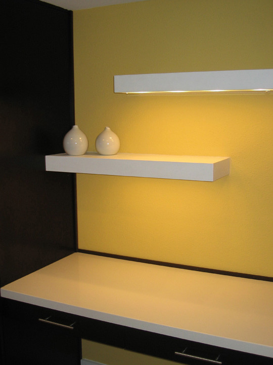 Immagine di un piccolo studio minimalista con pareti gialle e scrivania incassata