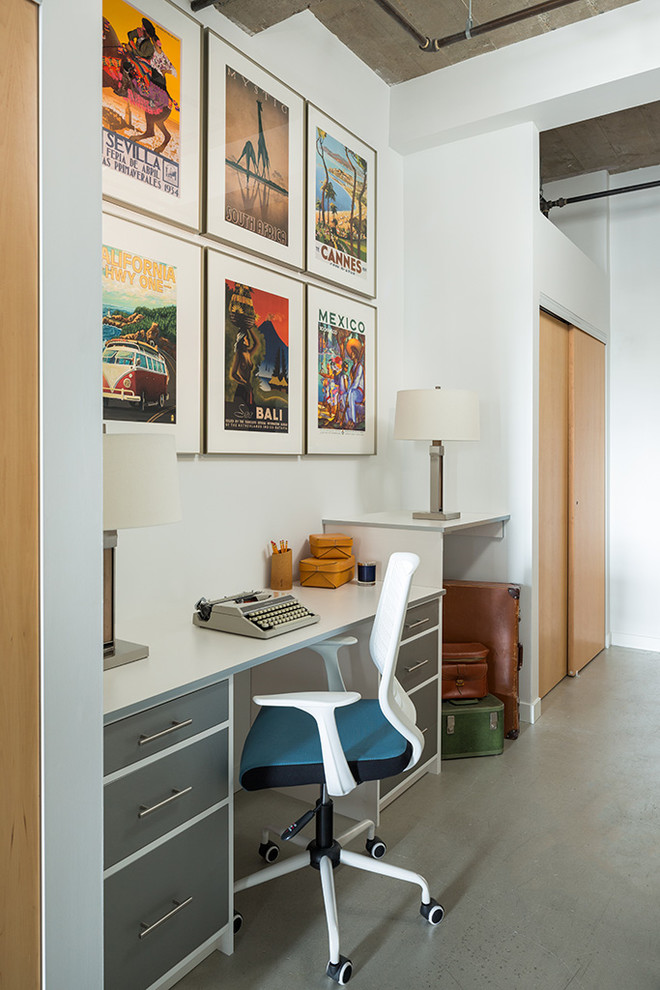 Cette photo montre un petit bureau industriel de type studio avec un mur blanc, sol en béton ciré et un bureau intégré.