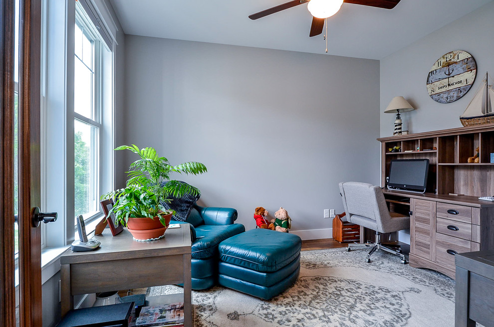 Kleines Maritimes Arbeitszimmer ohne Kamin mit Arbeitsplatz, grauer Wandfarbe, braunem Holzboden, freistehendem Schreibtisch und braunem Boden in Sonstige