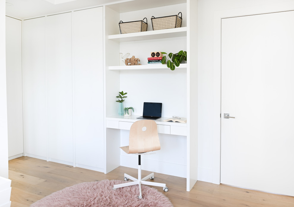 Diseño de despacho actual con paredes blancas, suelo de madera clara y escritorio empotrado