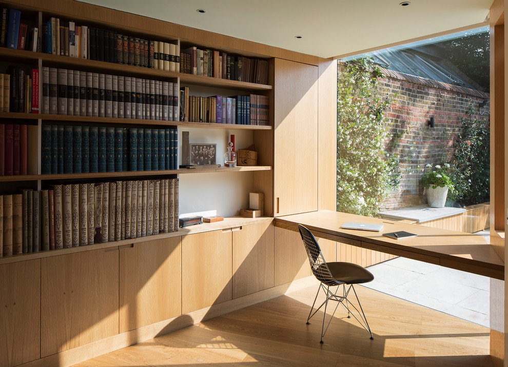 Inspiration för ett litet funkis hemmabibliotek, med beige väggar, mellanmörkt trägolv, ett inbyggt skrivbord och beiget golv