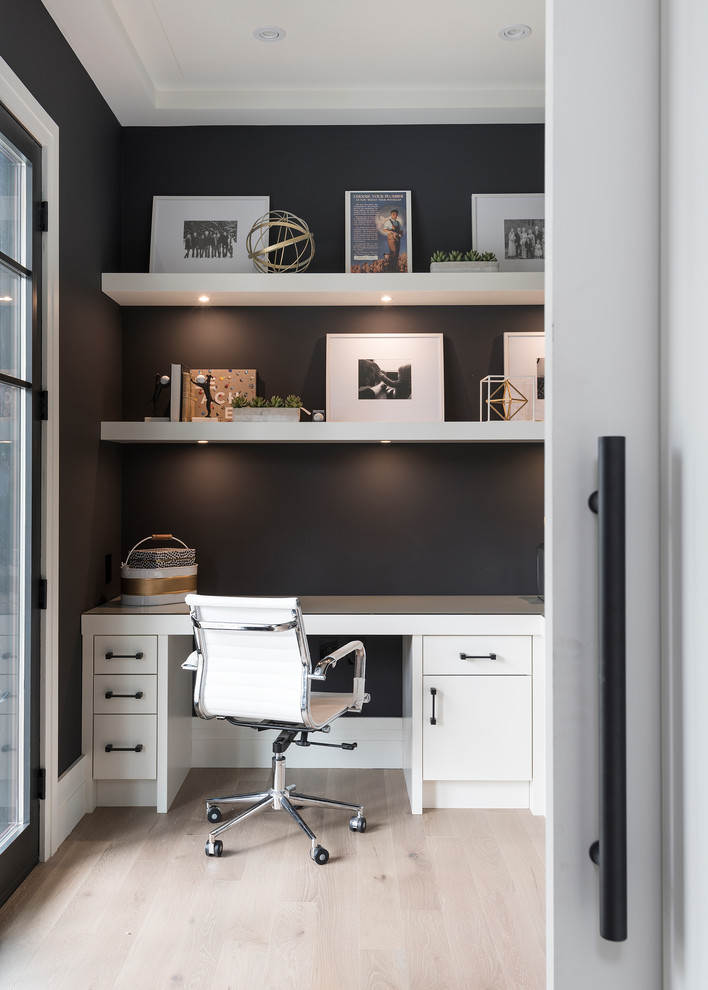 Cette image montre un bureau traditionnel avec un mur noir, parquet clair, un bureau intégré et un sol beige.