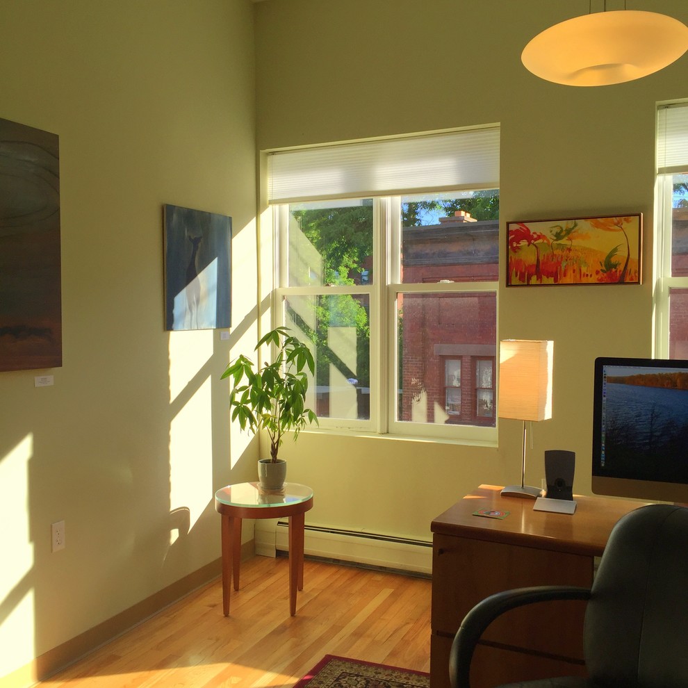 This is an example of a contemporary home office in Boston with green walls, medium hardwood flooring and a freestanding desk.