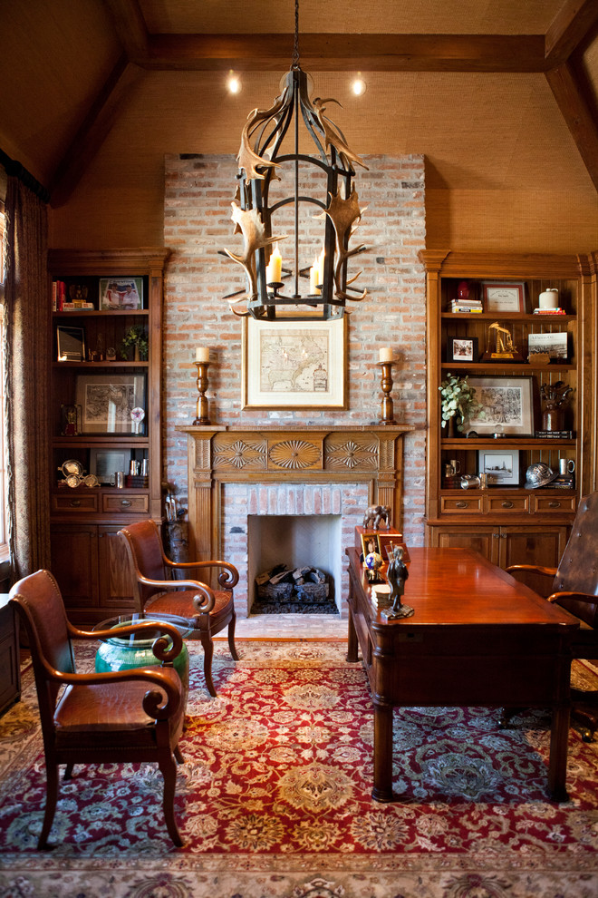 Imagen de despacho tradicional grande con paredes beige, suelo de madera en tonos medios, todas las chimeneas, marco de chimenea de ladrillo y escritorio independiente