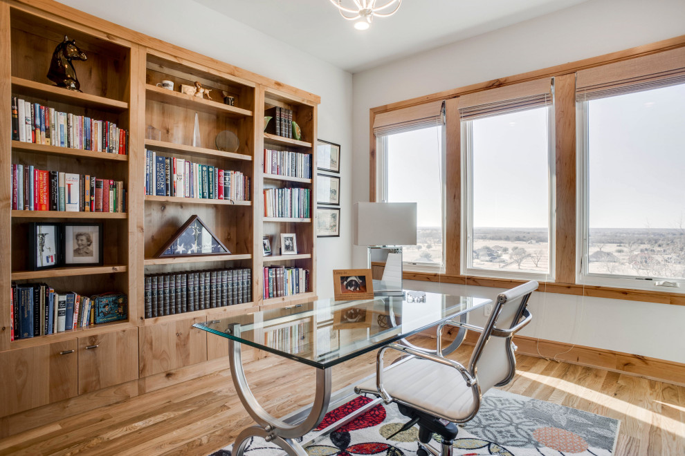 Modernes Arbeitszimmer mit weißer Wandfarbe, braunem Holzboden, freistehendem Schreibtisch und braunem Boden in Dallas