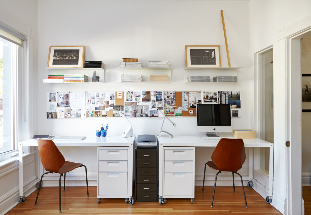 На фото: рабочее место в скандинавском стиле с белыми стенами, паркетным полом среднего тона и отдельно стоящим рабочим столом