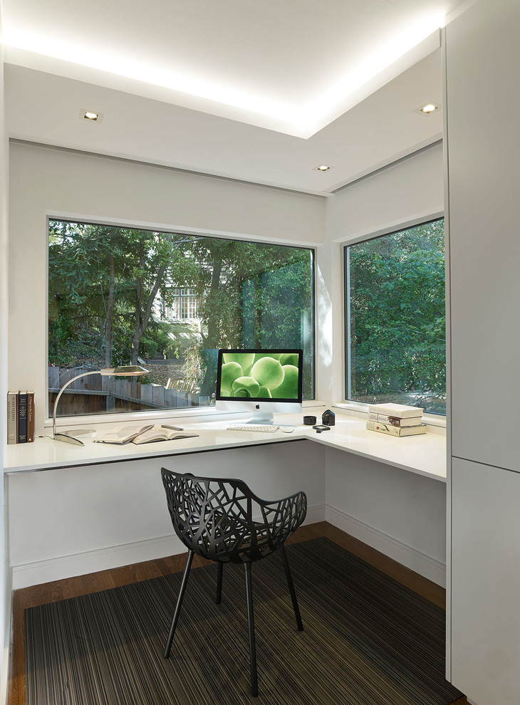 Example of a mid-sized minimalist built-in desk carpeted study room design in San Francisco with white walls