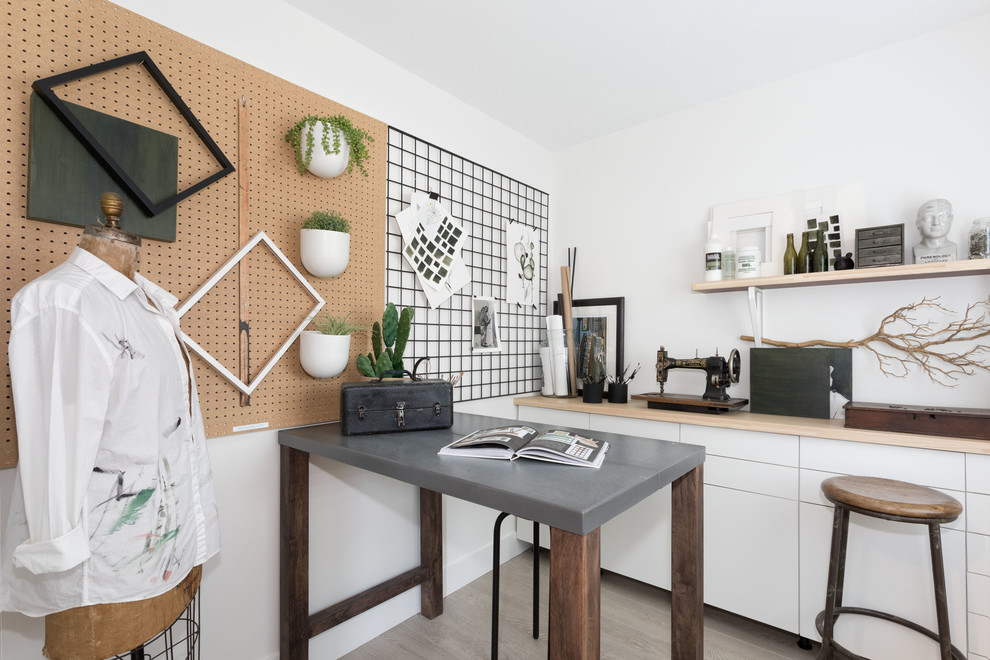 Imagen de sala de manualidades actual pequeña con paredes blancas, suelo laminado, escritorio empotrado y suelo beige
