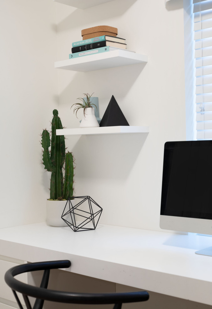 Cette image montre un petit bureau design avec un mur blanc, sol en stratifié, un bureau intégré et un sol beige.