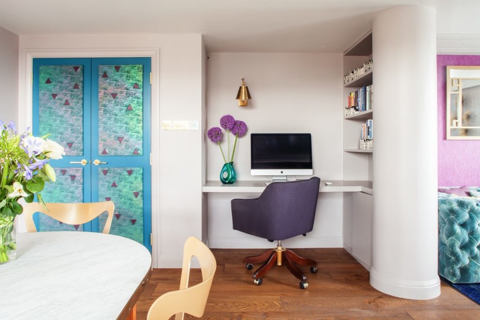 Cette photo montre un petit bureau chic avec un bureau intégré, un sol marron, un mur blanc et un sol en bois brun.