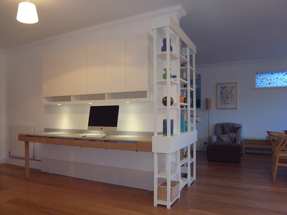 Immagine di uno studio design di medie dimensioni con pareti bianche, pavimento in legno massello medio e scrivania incassata