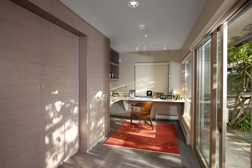 Modernes Arbeitszimmer mit beiger Wandfarbe, dunklem Holzboden und Einbau-Schreibtisch in Vancouver