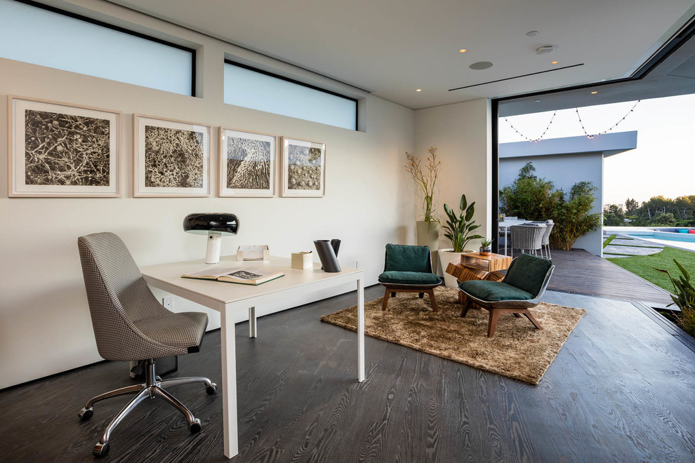 Inspiration for a contemporary home office in Los Angeles with dark hardwood flooring, no fireplace, a freestanding desk, brown floors and white walls.