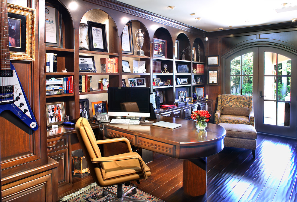 This is an example of a mediterranean study in Los Angeles with brown walls, dark hardwood flooring and a built-in desk.