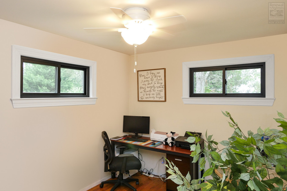 Cette image montre un bureau de taille moyenne avec un mur beige, un sol en bois brun, aucune cheminée, un bureau indépendant et un sol marron.