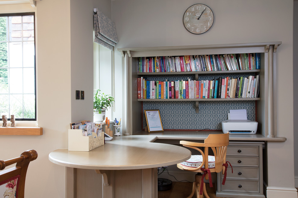 Cette photo montre un bureau chic avec un mur gris, un sol en bois brun, un bureau intégré et un sol marron.