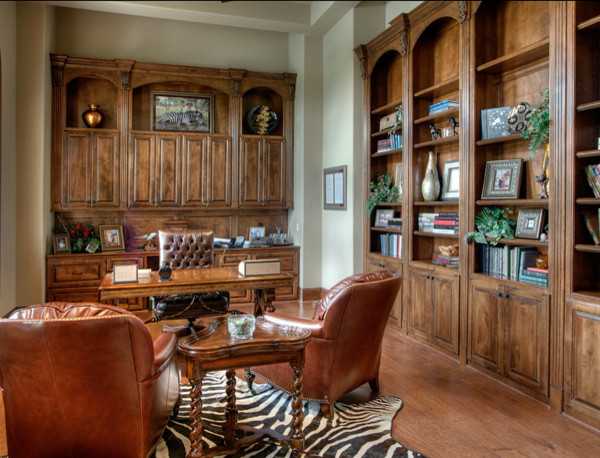 Modelo de despacho clásico extra grande con biblioteca, paredes beige, suelo de madera en tonos medios y escritorio independiente