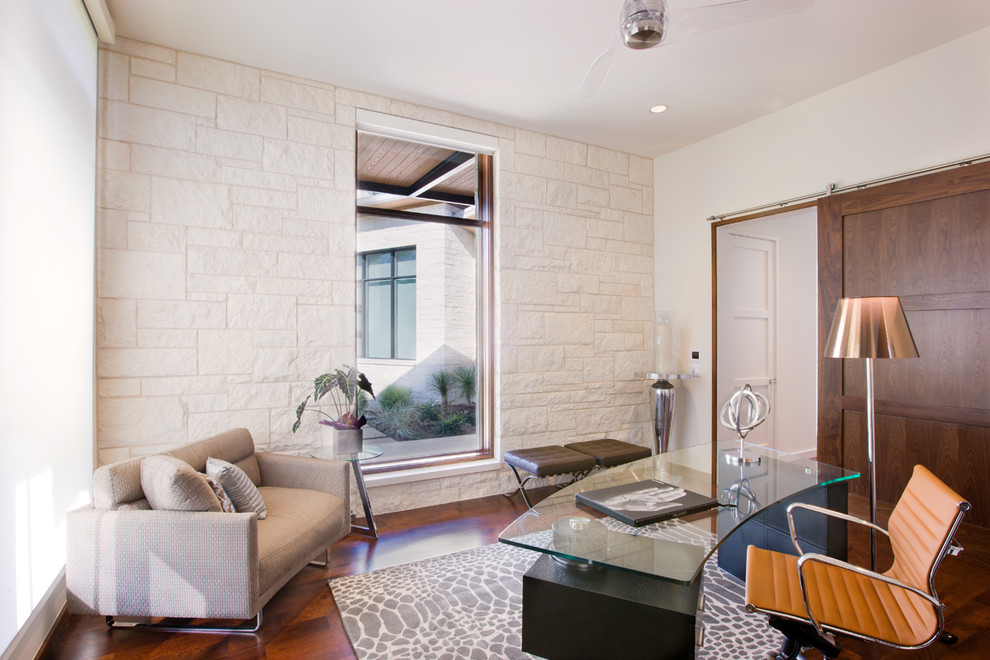 Contemporary study in Austin with white walls, medium hardwood flooring and a freestanding desk.