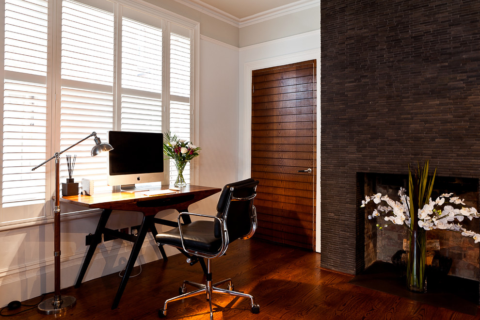 Inredning av ett modernt arbetsrum, med grå väggar, mörkt trägolv och ett fristående skrivbord